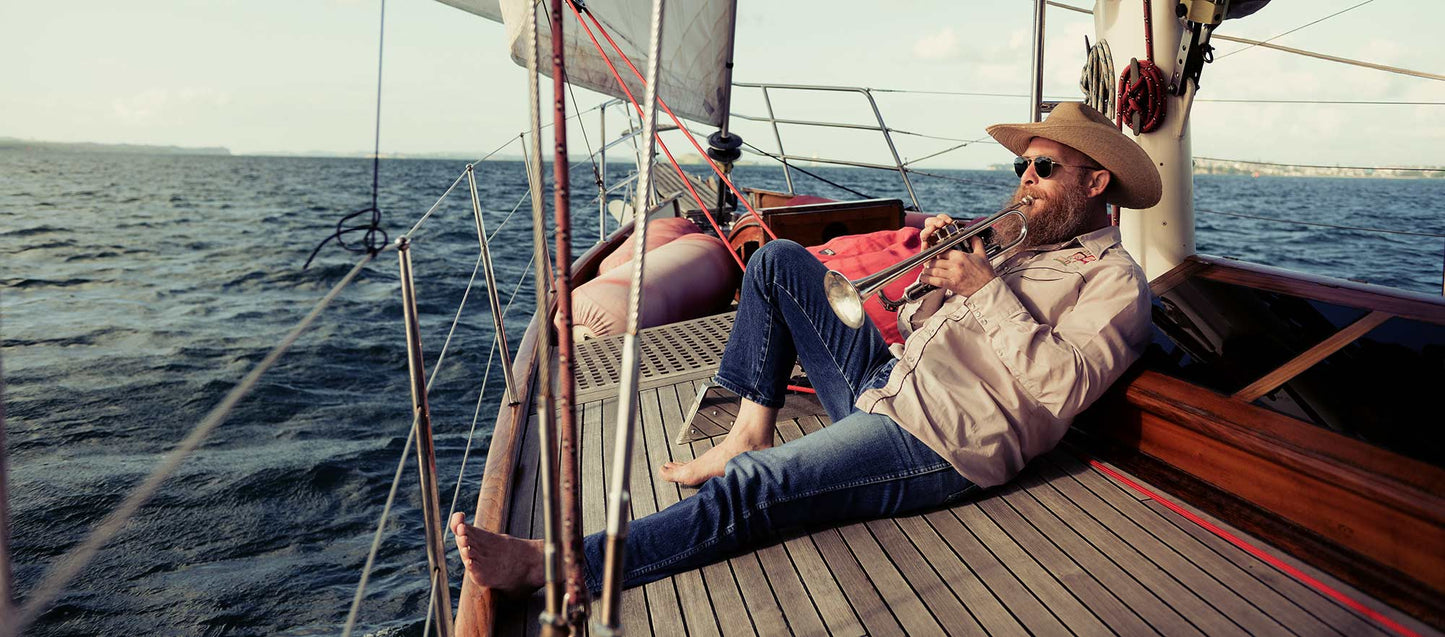 man with beard on deck playing trumpet